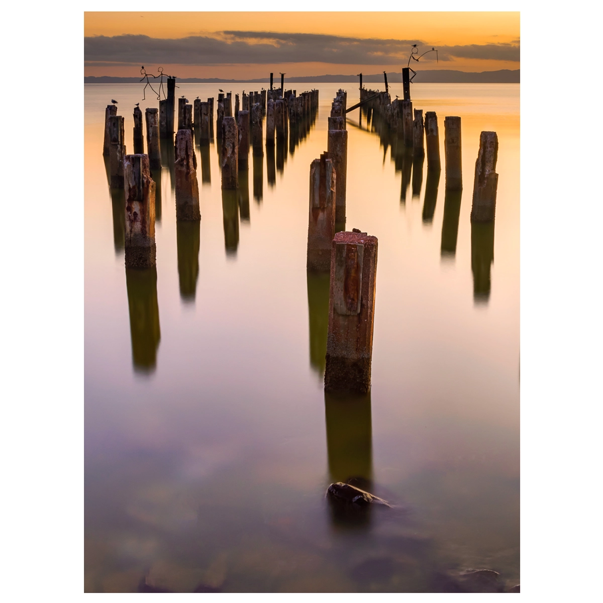 Burke Street Wharf in Thames at sunset, with only the pillars remaining and smooth water from long exposure.