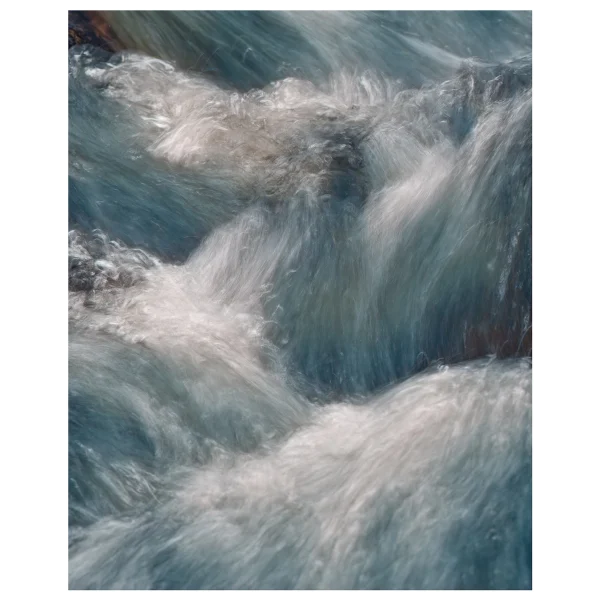 Close-up long exposure of water flowing over rocks, showing detailed movement in the stream.