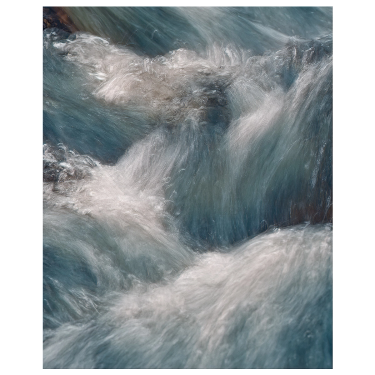 Close-up long exposure of water flowing over rocks, showing detailed movement in the stream.