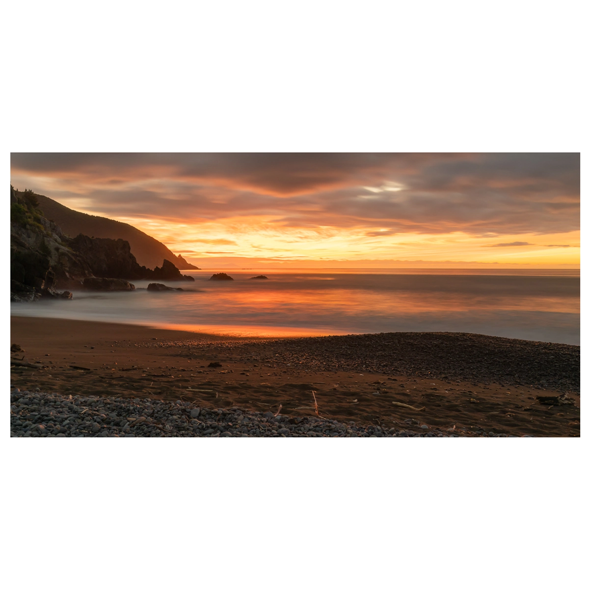 Sunrise at Rarangi Beach with large rocks in the sea, long exposure.