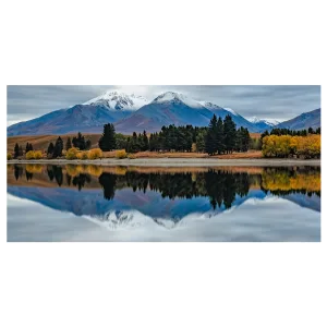 Long exposure photo of Lake Camp, Ashburton Lakes, early morning with reflections of autumn trees and snow-capped mountains.