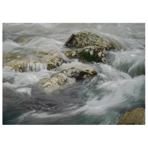 Close-up long exposure of water rushing around rocks in a river, with detailed flow patterns