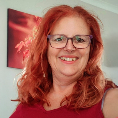 Jacqui Stokes standing in her office with one of her canvas photographs displayed on the wall behind her.