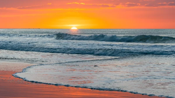 Makorori Beach Sunrise – Waves on Shore with Orange Sky Reflected in Wet Sand