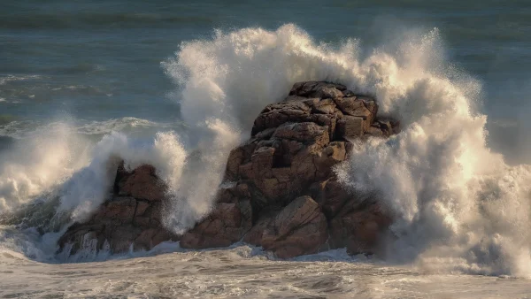 Crashing Wave – Sunlit Ocean Wave Against Rock with Sea Foam